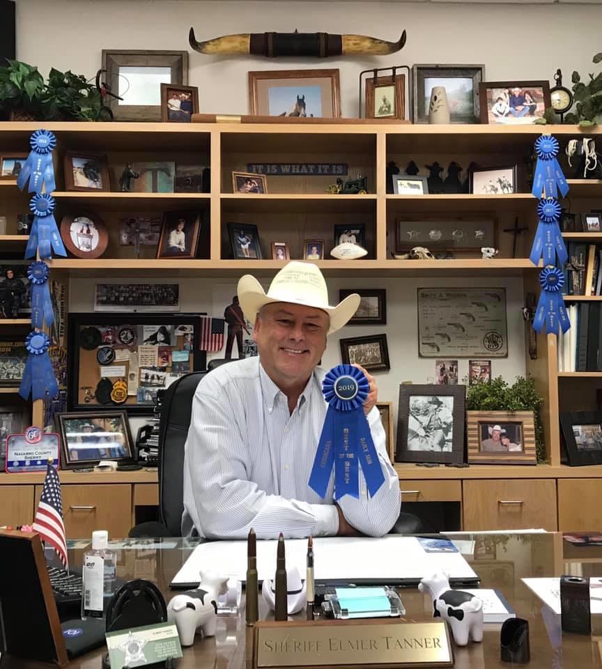 Sheriff Tanner holding up a blue ribbon