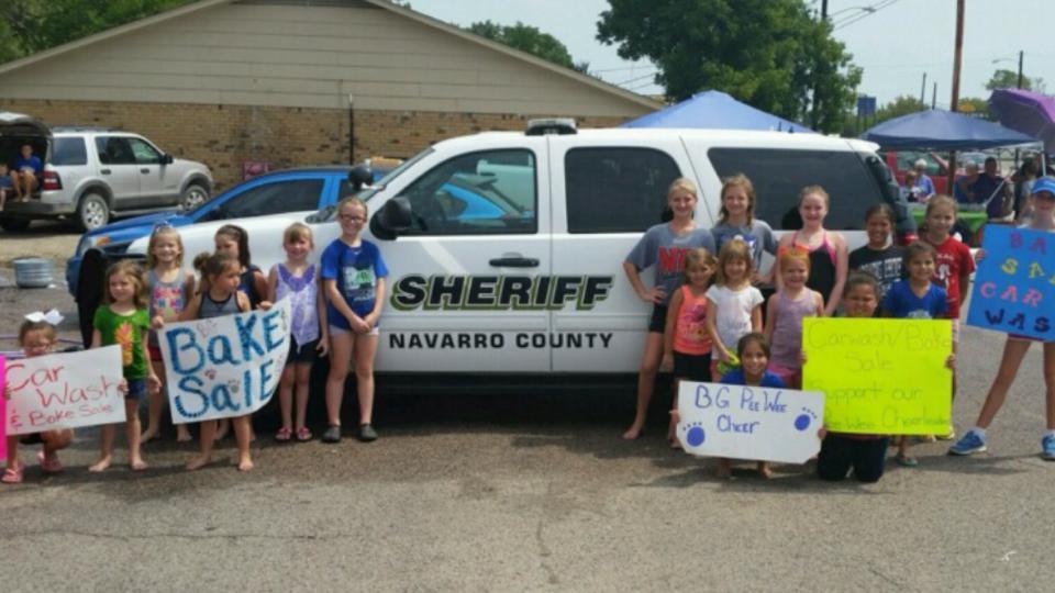 Blooming Grove peewee cheerleaders pose with NCSO police vehicle after washing it