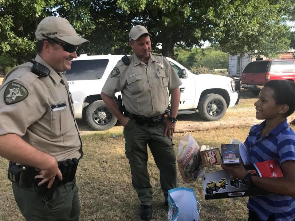 Josh Erwin smiles at two police officers with his arms full of gifts