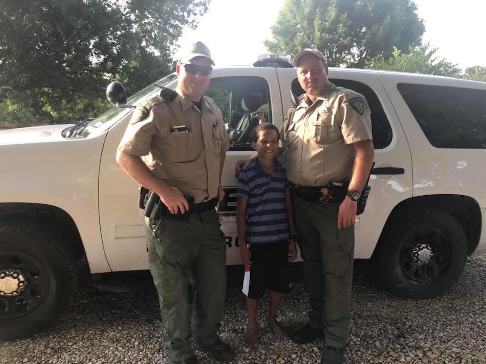 Josh Erwin stands and smiles between two police officers