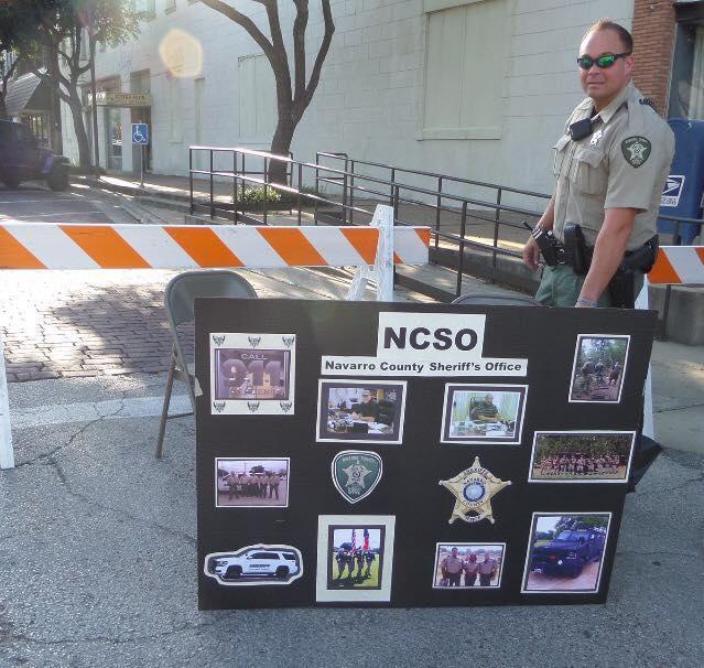 Deputy Eric Wilson pose next to a NCSO poster
