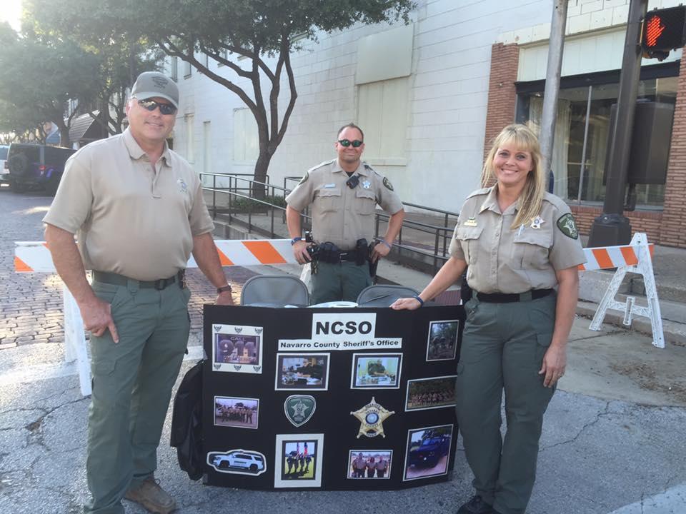 Sheriff Tanner, Sgt. Melanie Cagle and Deputy Eric Wilson pose next to a NCSO poster