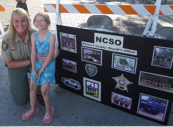Sgt. Melanie Cagle and a child pose next to a NCSO poster