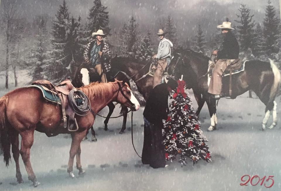 Cowboys on horses watch a man hanging a decoration on a Christmas tree