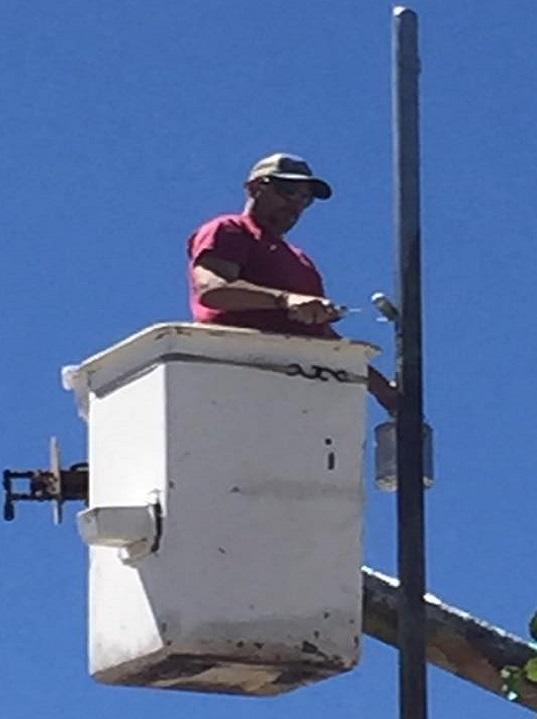 Man in bucket lift installing a flag pole outside