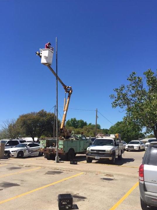 Man in bucket lift installing a flag pole outside