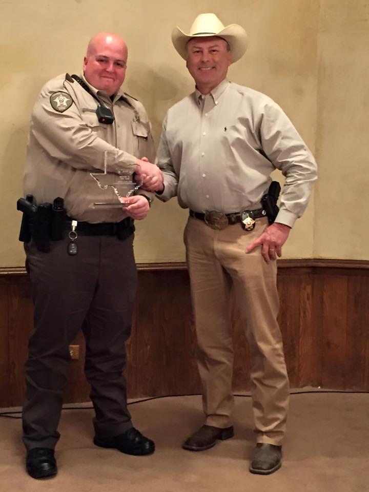 Deputy Loftis shaking hands with Sheriff Tanner as he holds his award