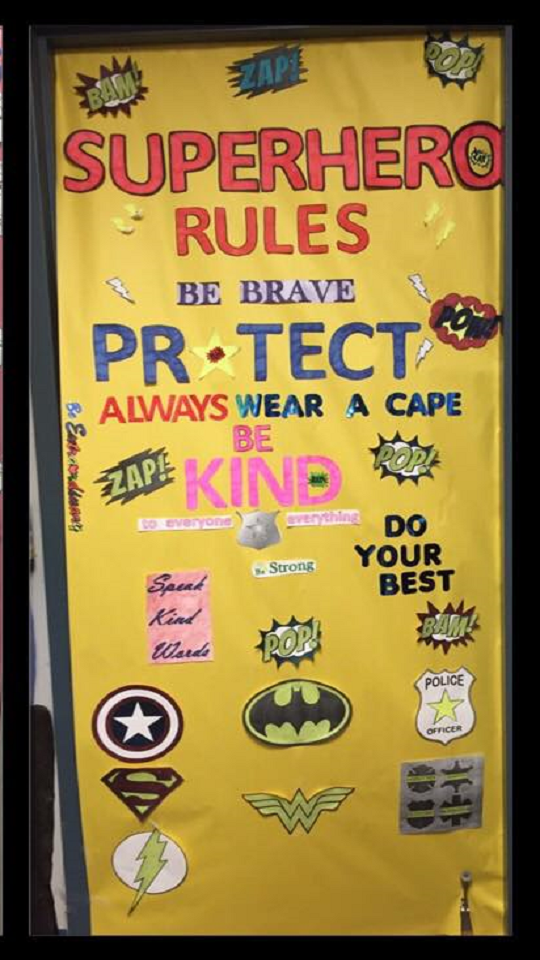 Door decoration: "Superhero rules: be brave, protect, always wear a cape, be kind, do your best" and other various superhero symbols