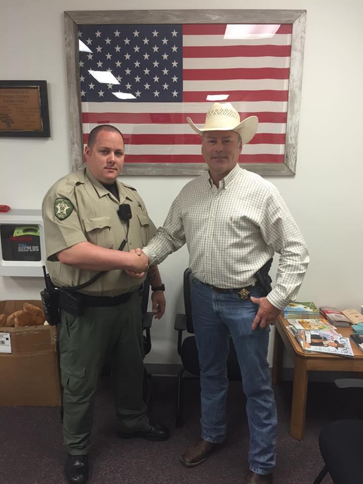 Michael Milligan shakes hands with Sheriff Tanner after being promoted 