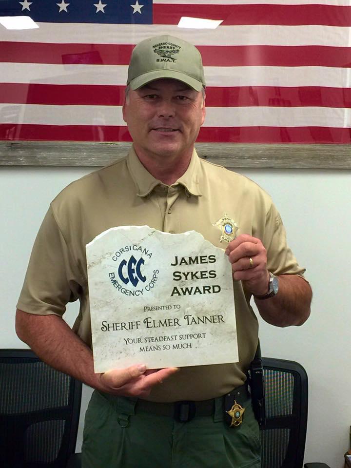 Sheriff Tanner stands holding the James Skyes Award