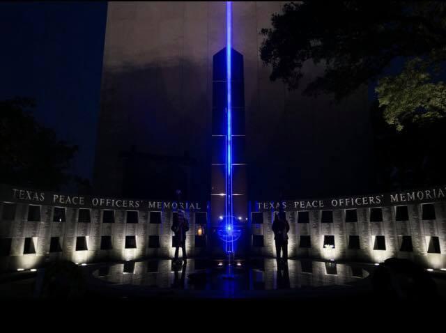 The Texas Peace Officers Memorial illuminated against the dark sky